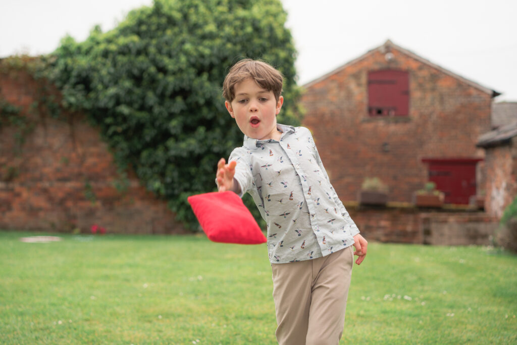 handsome boy playing cornhole at a wedding