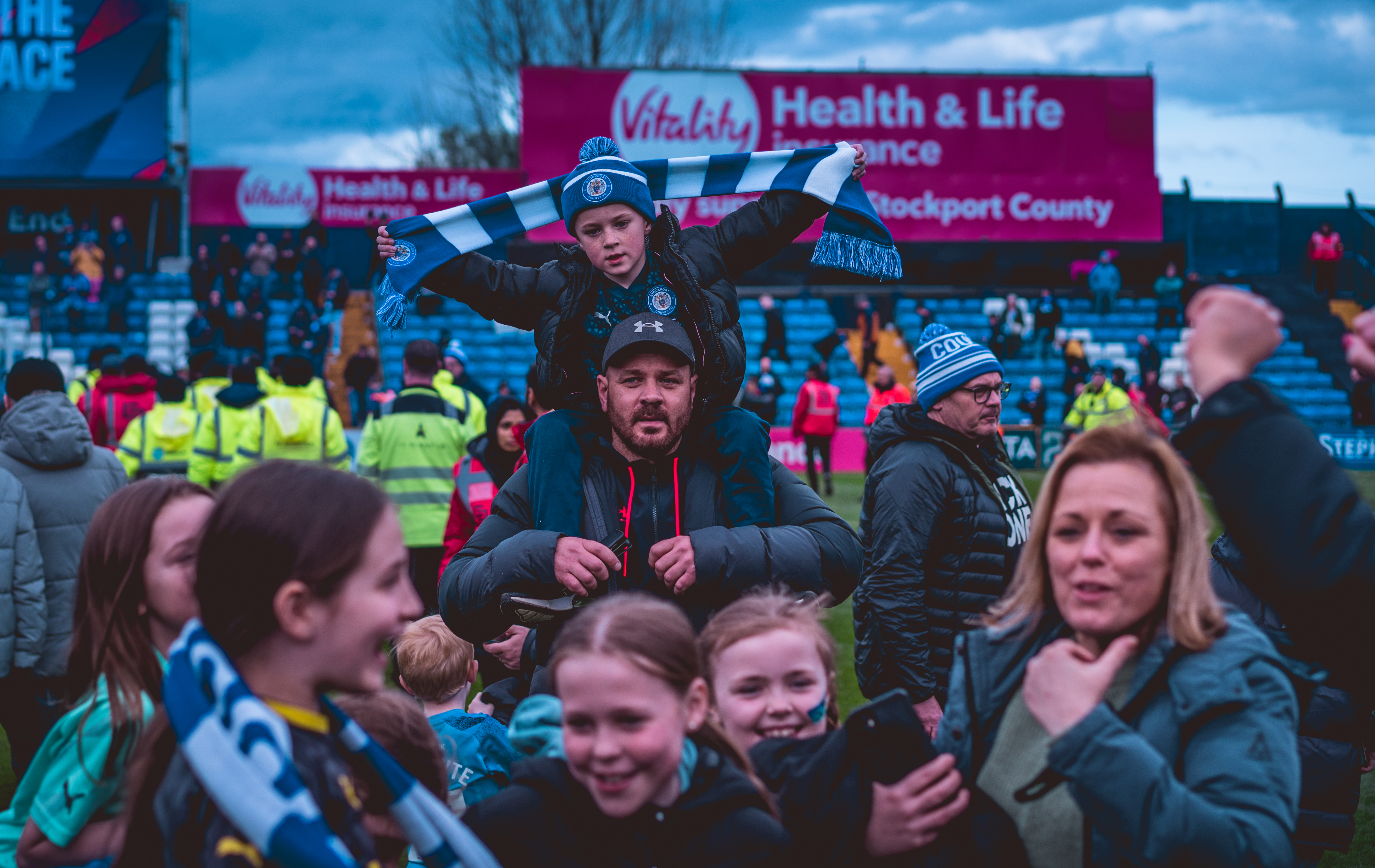 fans of all ages on the pitch celebrating stockport county promotion